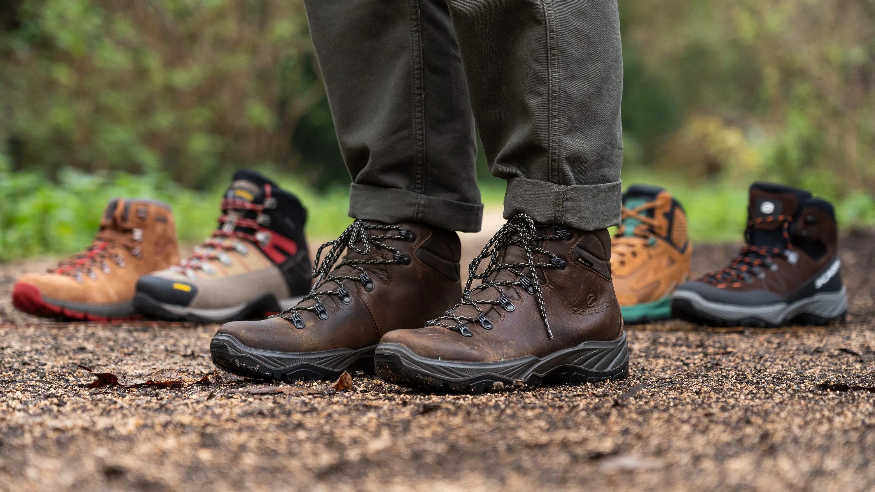 Different types of proper walking boots displayed on outdoor terrain showing various styles and materials
